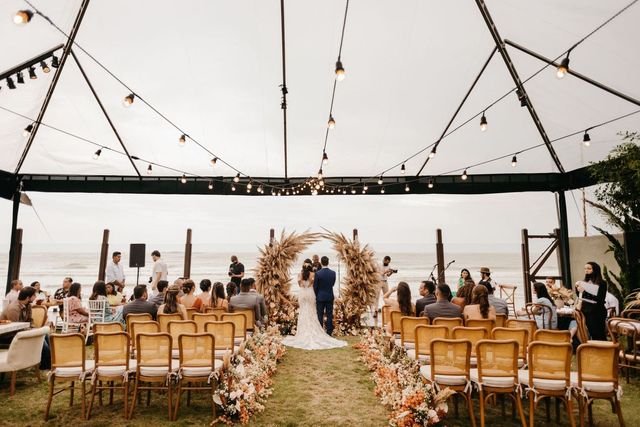 Outdoor wedding ceremony under a canopy by the sea